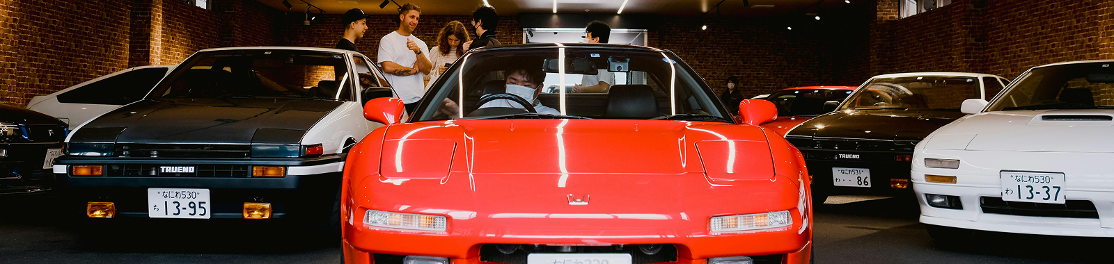 Japanese cars in a garage with people around it